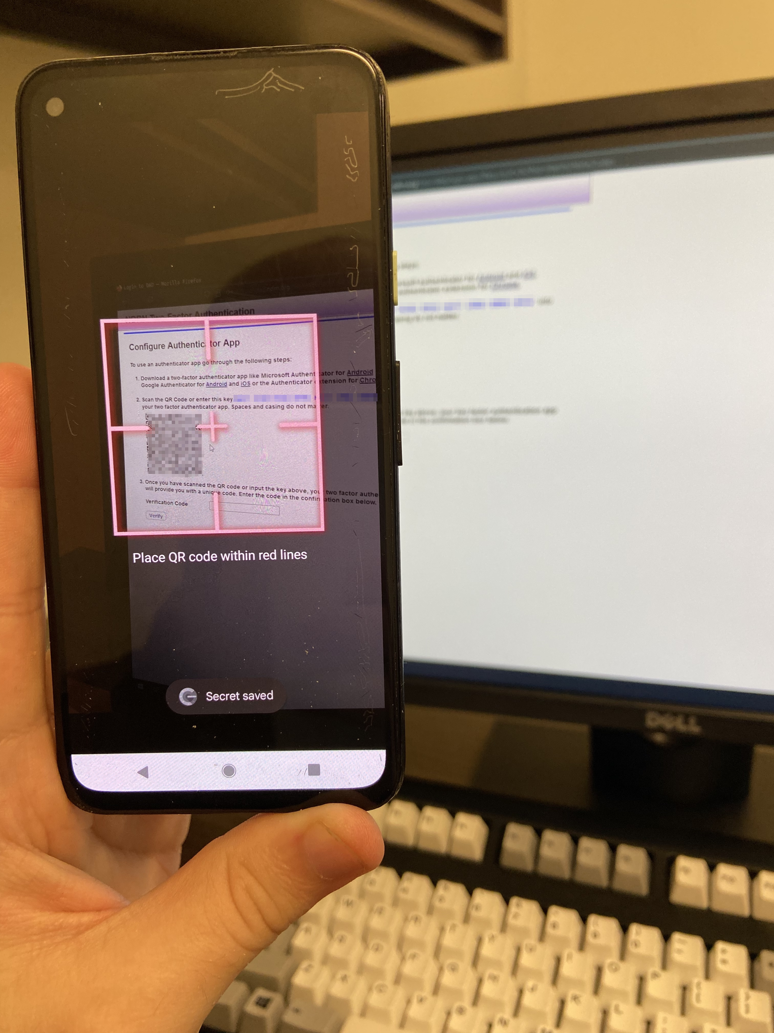 An android phone in the google authenticator "QR code scan" interface, pointed at a QR code on a computer screen